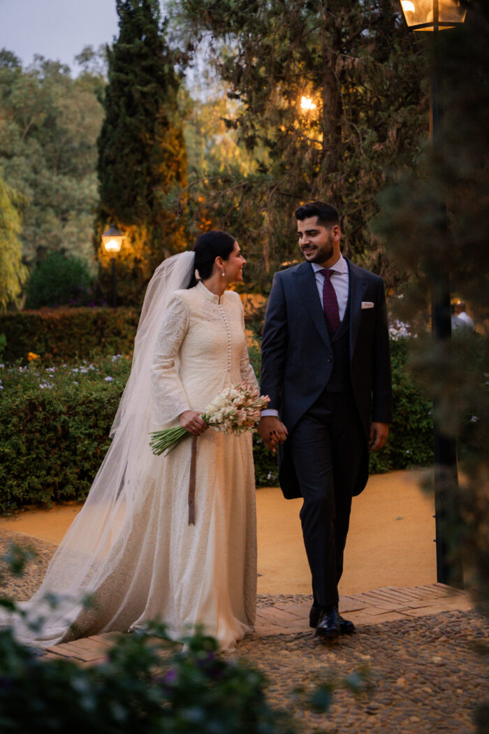 novios caminando en jardín boda elegante vestido clásico con velo largo